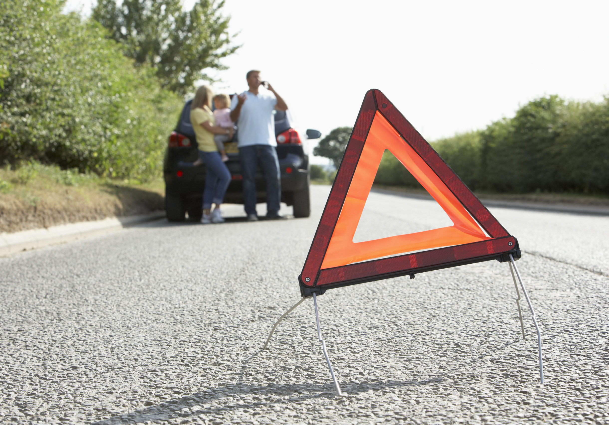 Family Broken Down On Country Road With Hazard Warning Sign In F